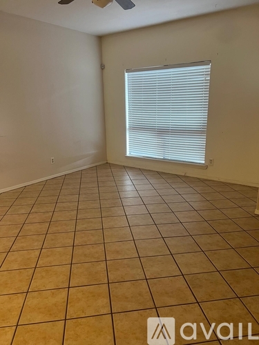 A room with tiled flooring and a window with blinds.