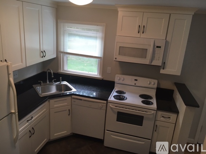 A kitchen with white cabinets and black countertops.