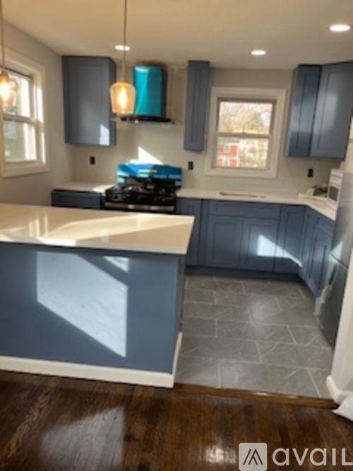 A kitchen with a white counter top and blue cabinets.