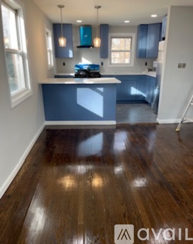 A kitchen with wooden floors and a blue island.