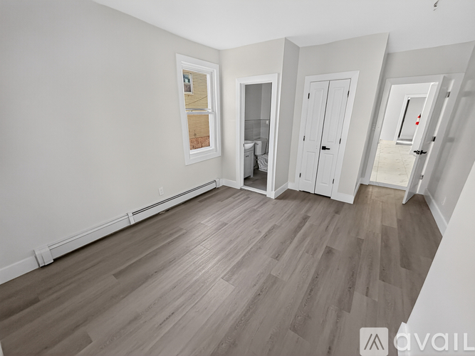 A spacious room with wood flooring and white walls.