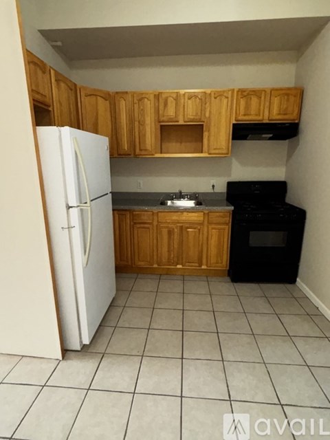 A kitchen with a white refrigerator, black oven, and wooden cabinets.