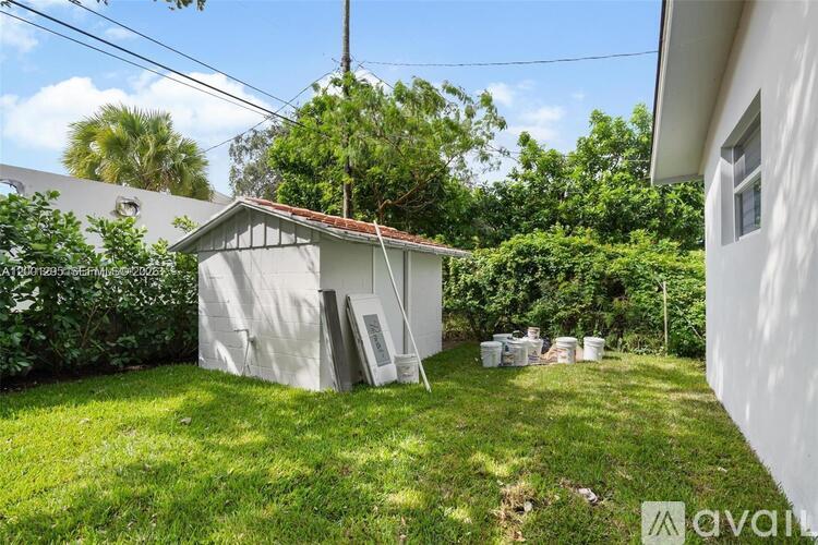 A backyard with a shed and a few buckets on the grass.