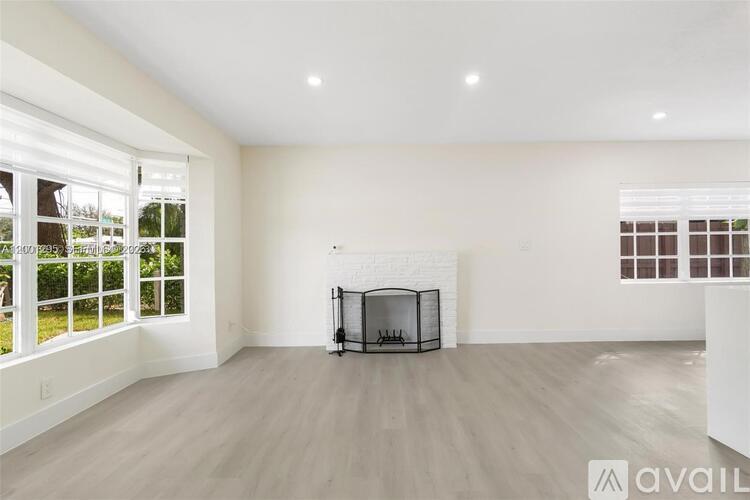 A spacious living room with a fireplace and large windows.