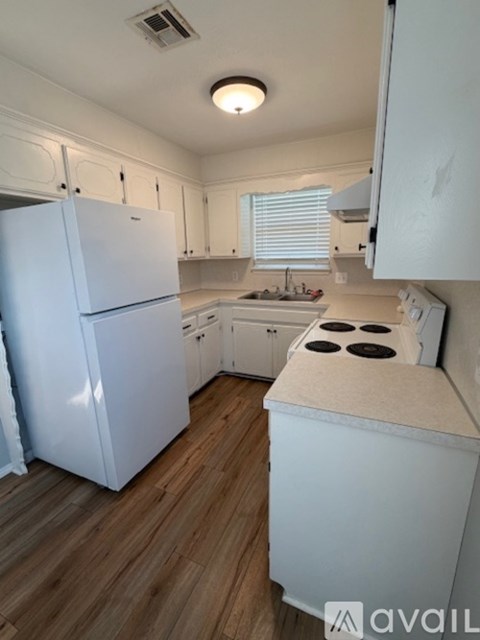 A kitchen with white appliances and wooden floors.