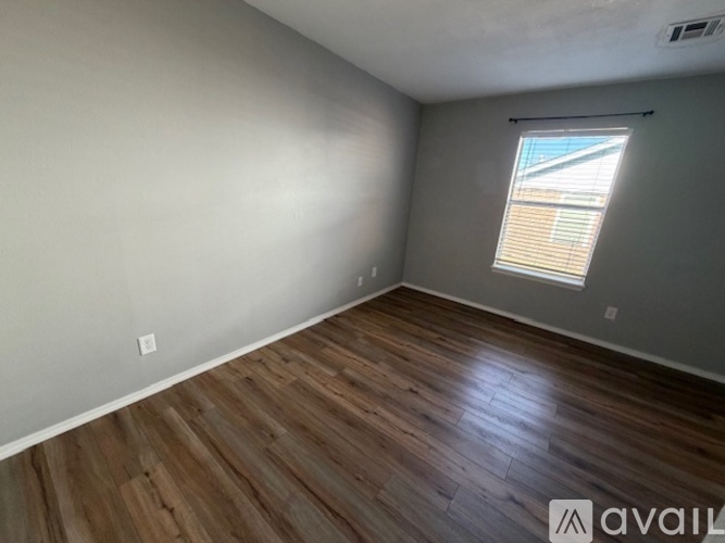 A room with wooden flooring and a window with blinds.