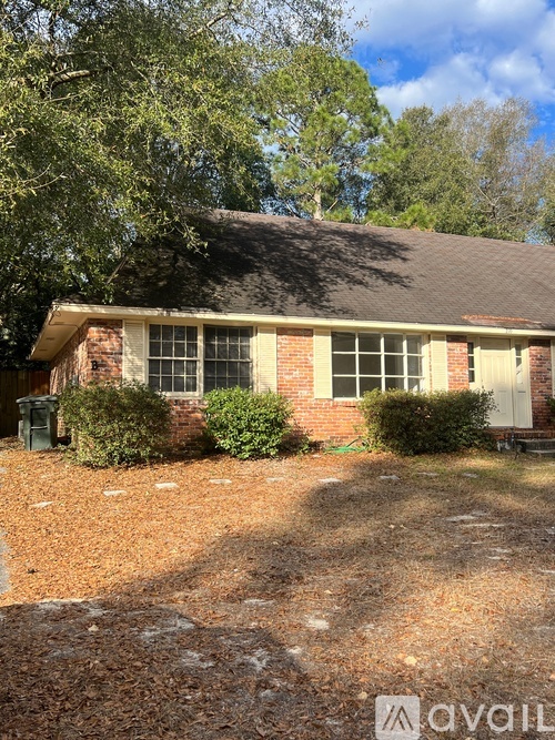 A house with a brown roof and a white door is surrounded by trees.
