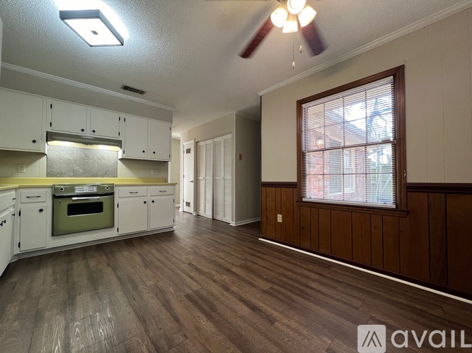 A kitchen with white cabinets and a green oven is available for rent.