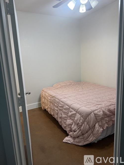 A bedroom with a bed and a window with blinds.