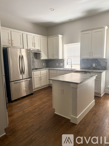 A kitchen with white cabinets and a stainless steel refrigerator.