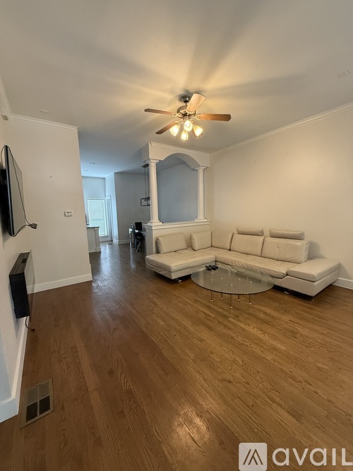 A living room with a white couch and a ceiling fan.