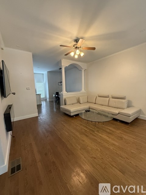 A living room with a white couch and a ceiling fan.