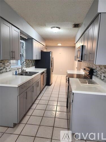 A kitchen with white cabinets and a black fridge.
