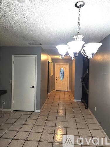 A hallway with a chandelier and a door at the end.