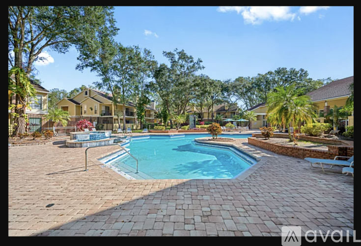 A pool surrounded by a brick patio and trees.