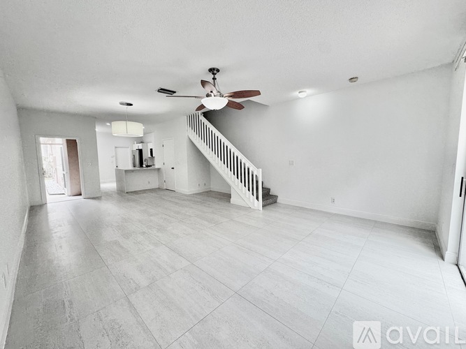 A spacious empty room with a fan and a staircase.