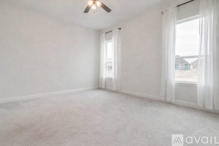 A spacious room with a ceiling fan and carpeted floor.
