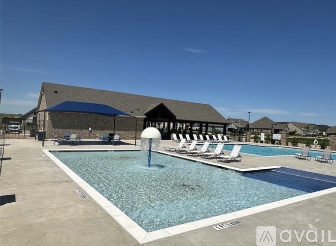 A large swimming pool with a fountain in the middle and sun loungers around it.