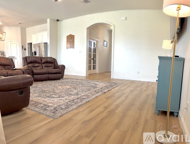 A living room with a brown leather couch and a rug.