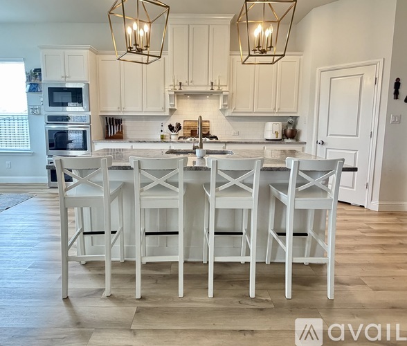 A kitchen with white chairs and cabinets.