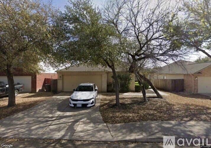 A white car is parked in a driveway in front of a house.
