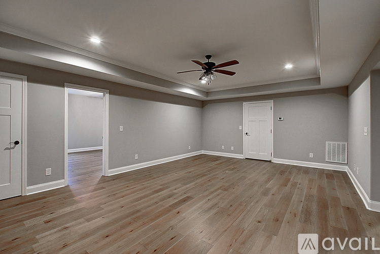 A spacious room with wooden flooring and a ceiling fan.