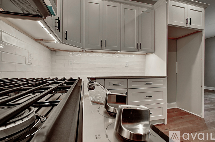 A kitchen with a stove top oven and a white tile backsplash.