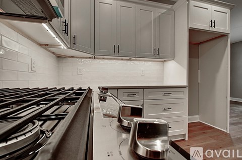 A kitchen with a stove top oven and a white tile backsplash.