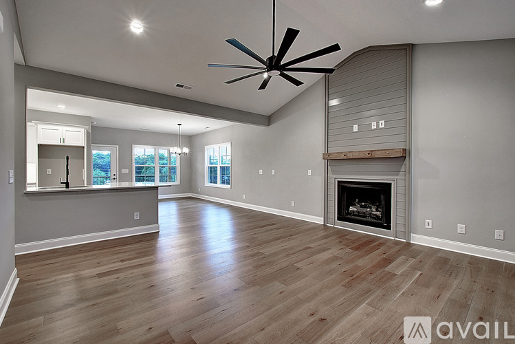 A spacious living room with a fireplace and a ceiling fan.