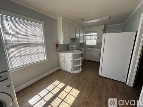 A kitchen with white appliances and wooden floors.