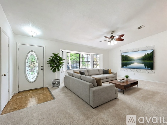 A living room with a grey sofa, a wooden coffee table, a ceiling fan, and a large painting on the wall.