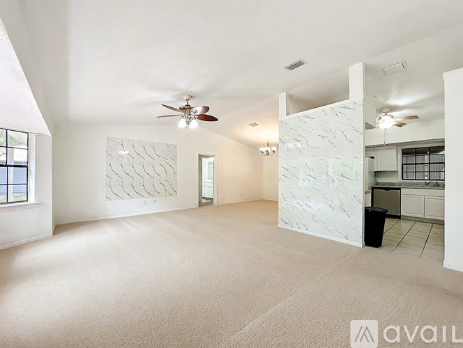A spacious room with a ceiling fan and a carpeted floor.