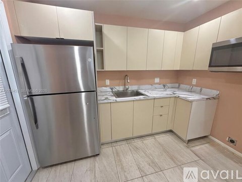 A kitchen with a stainless steel refrigerator and a sink.