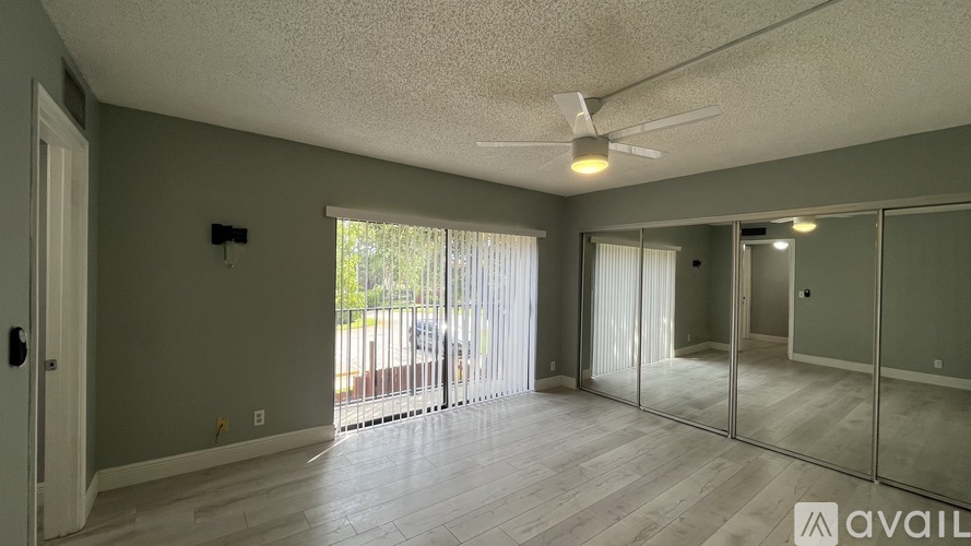 A spacious room with a sliding glass door leading to a balcony.