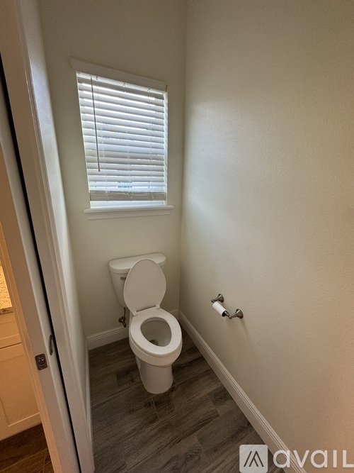 A white toilet in a small bathroom with a window.