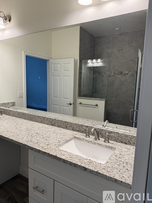 A bathroom with a sink, mirror, and a blue door.