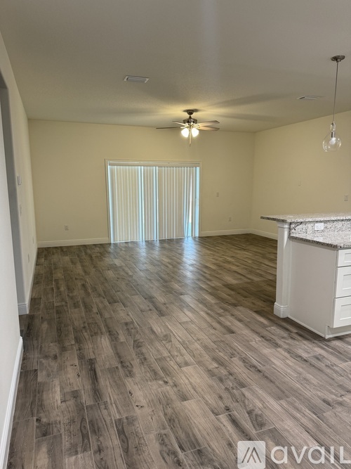 A spacious room with wooden flooring and a ceiling fan.