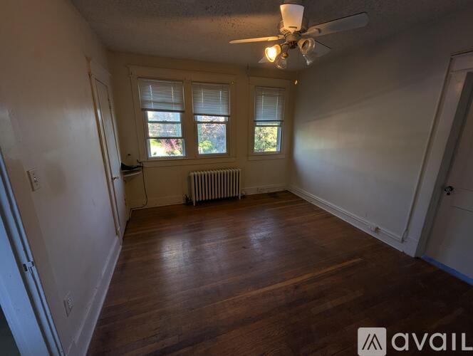A room with a ceiling fan and a window with blinds.