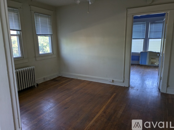 A room with wooden floors and white walls, with a window and a radiator.