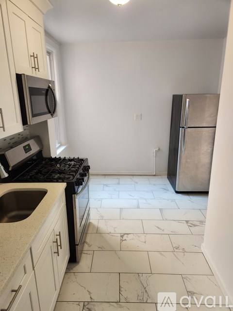 A kitchen with a black stove top oven and a silver refrigerator.