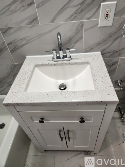 A white sink with a marble top is installed in a bathroom.