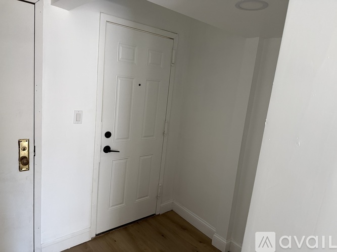 A white door with a brass handle is in a room with white walls.
