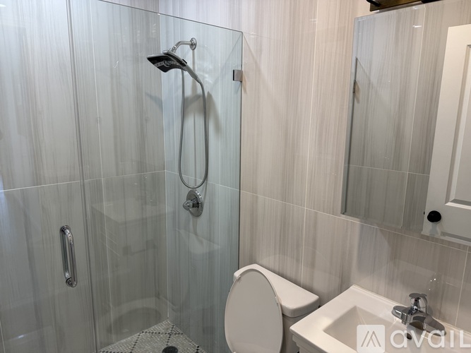 A white toilet sits next to a sink in a glass-walled shower.