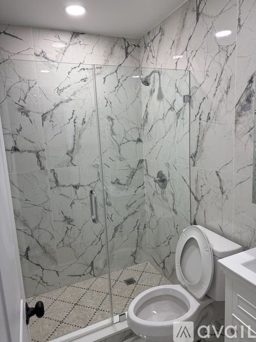 A bathroom with a marble wall and a toilet.