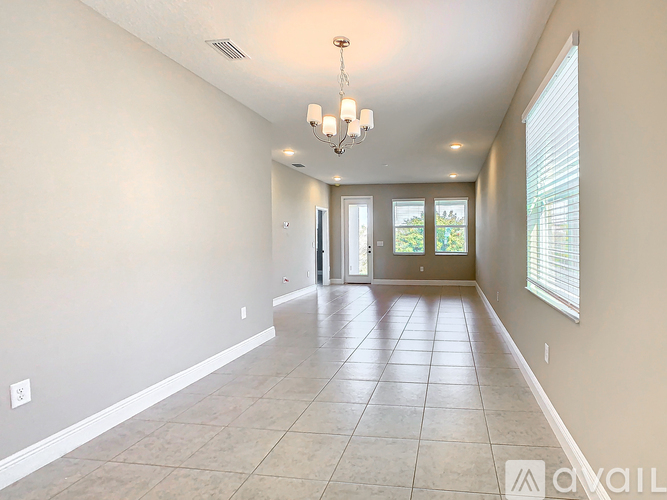 A spacious room with tiled flooring and a chandelier.