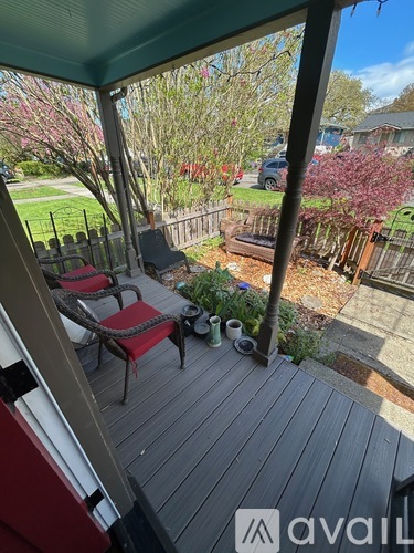 A wooden deck with a red chair and a table with a plant on it.