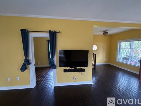 A living room with a television and a window with curtains.