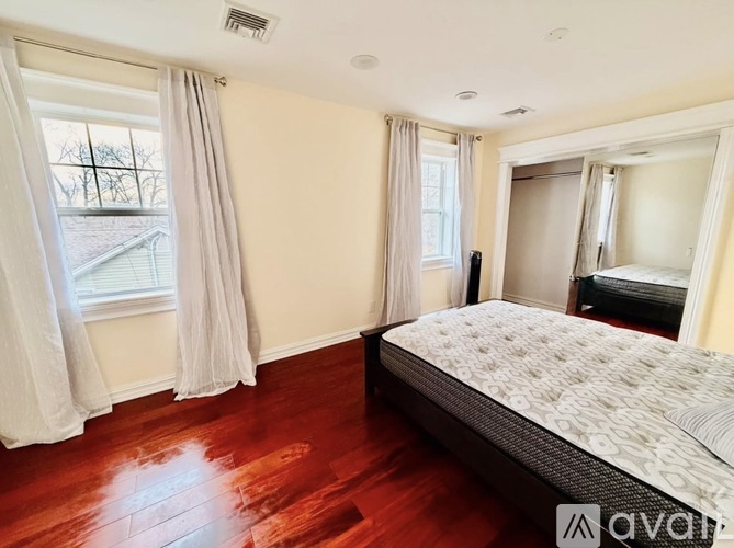 A bedroom with a large bed and a window with curtains.