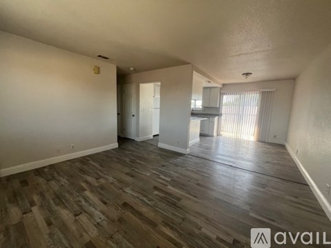 A spacious room with wooden flooring and white walls.
