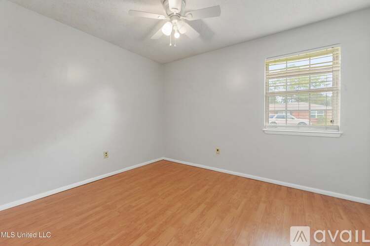 A room with a ceiling fan and a window with a view of a building outside.